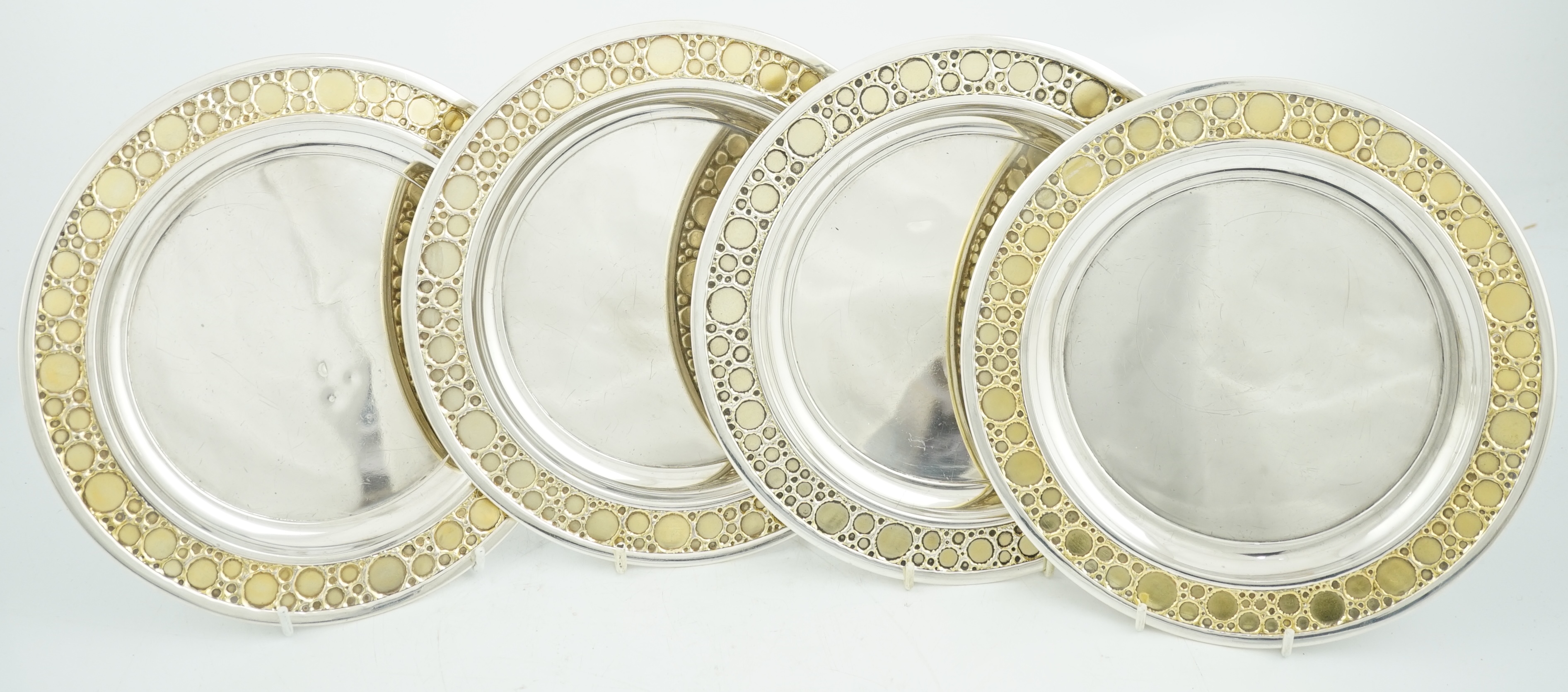 A set of four Elizabeth II Stuart Devlin parcel gilt silver circular plates